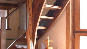 Una escalera de madera con diseño rústico, una pequeña silla de madera y un objeto rojo en el suelo.