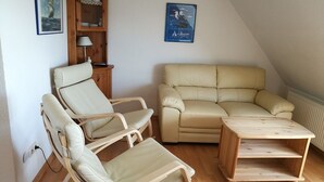 Un accogliente soggiorno con un divano color beige, due poltrone a dondolo e un tavolino in legno.