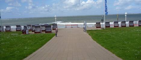A paved walkway leading to beachside seating areas with a view of the ocean.