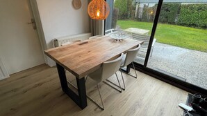 Ein Essbereich mit Holztisch und -stühlen, einem Heizkörper und Blick auf den Garten durch eine Glastür.