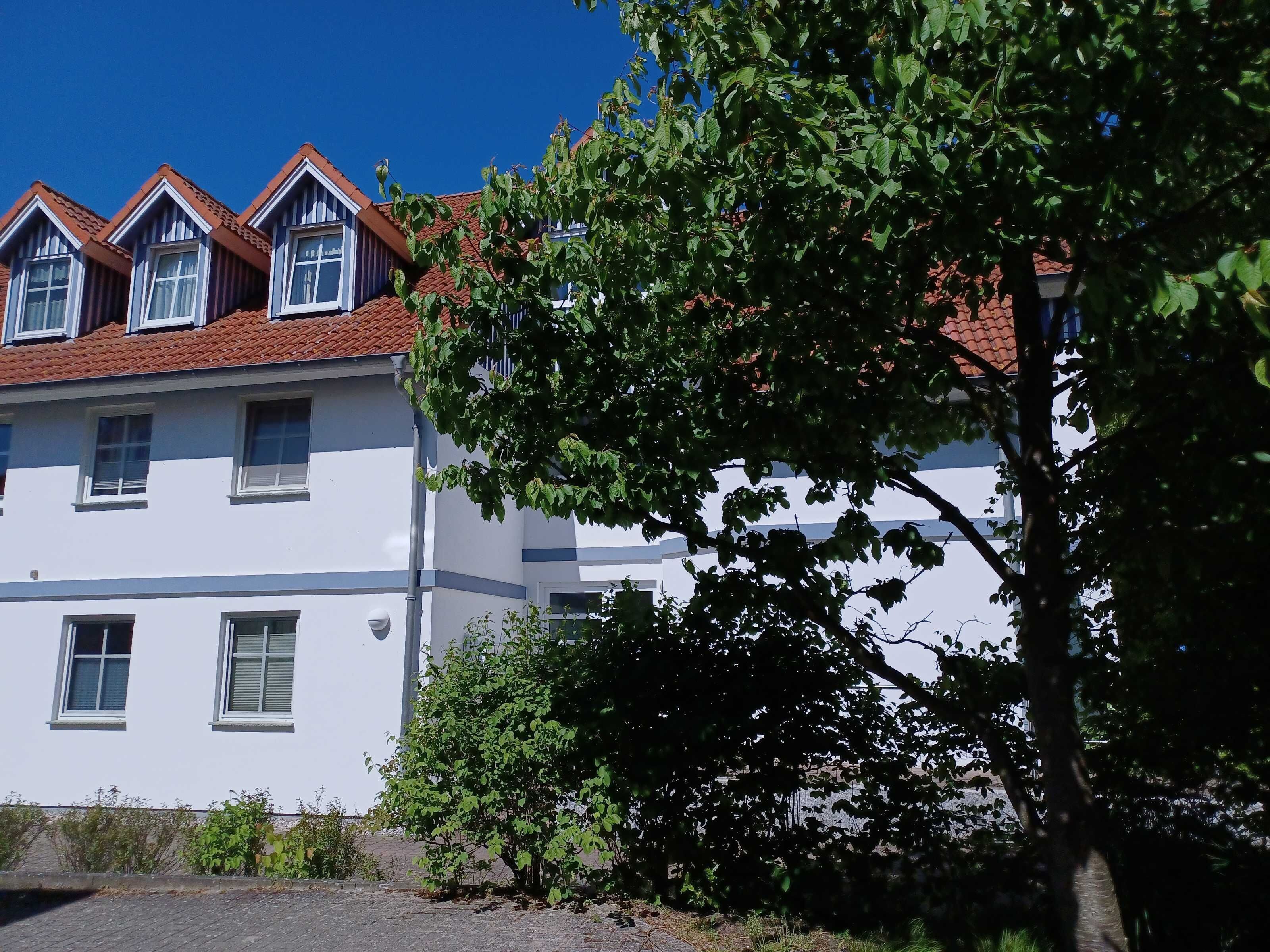 A white building with multiple windows and a red-tiled roof.