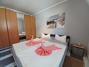 A hotel room with a bed, a wooden wardrobe, a nightstand, and a painting on the wall.