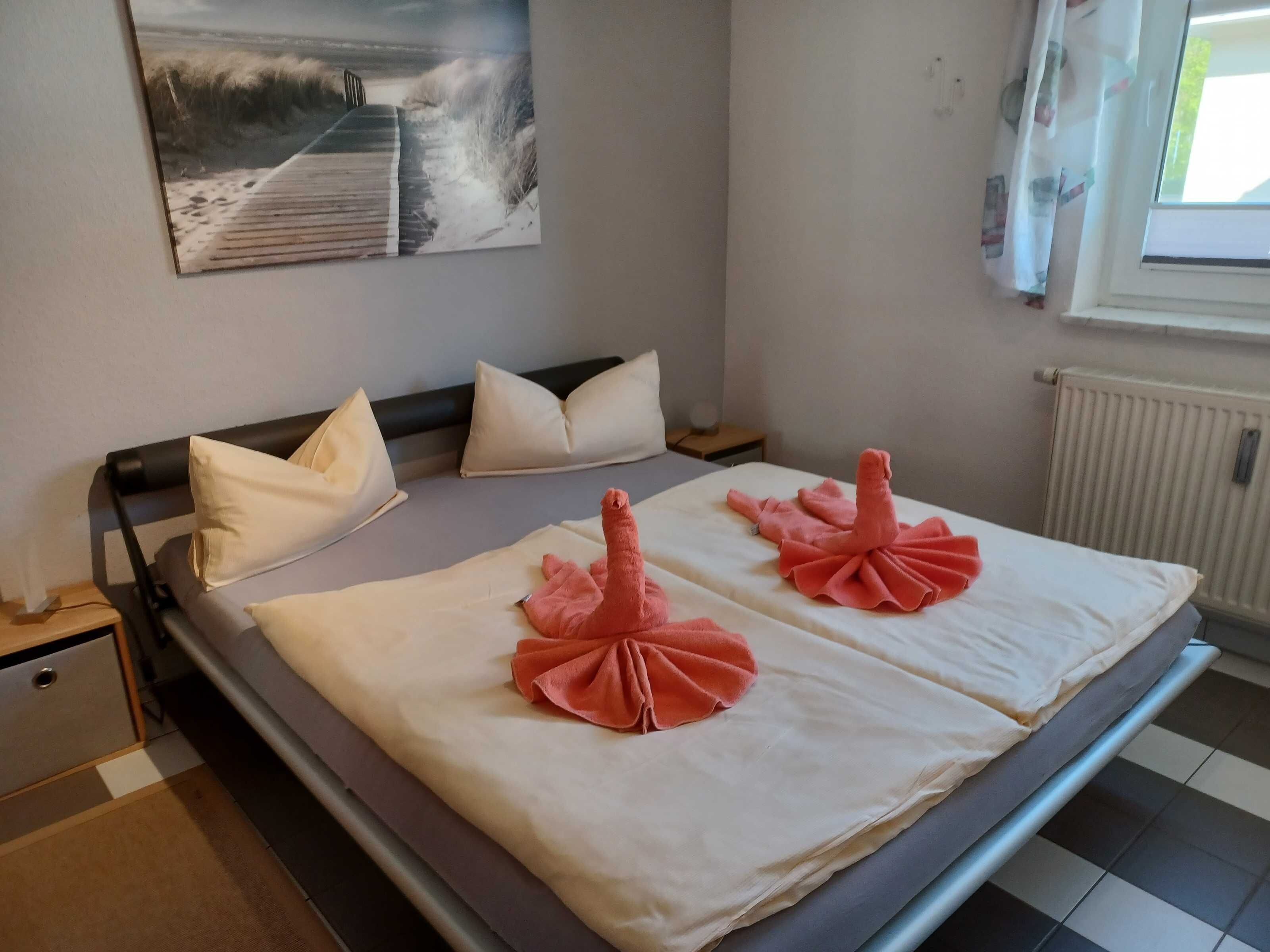 Ein Bett mit einer weißen Matratze, zwei Kissen und einer Zierde aus einem rosa Handtuch.