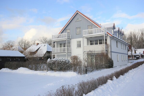 A two-story house with a balcony, a snow-covered roof, and a clear sky.