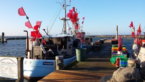A dock with boats, a wooden walkway, and a signboard. - cozy 3-room apartment in Timmendorf-Strand with sea view (Timmendorf-Strand)