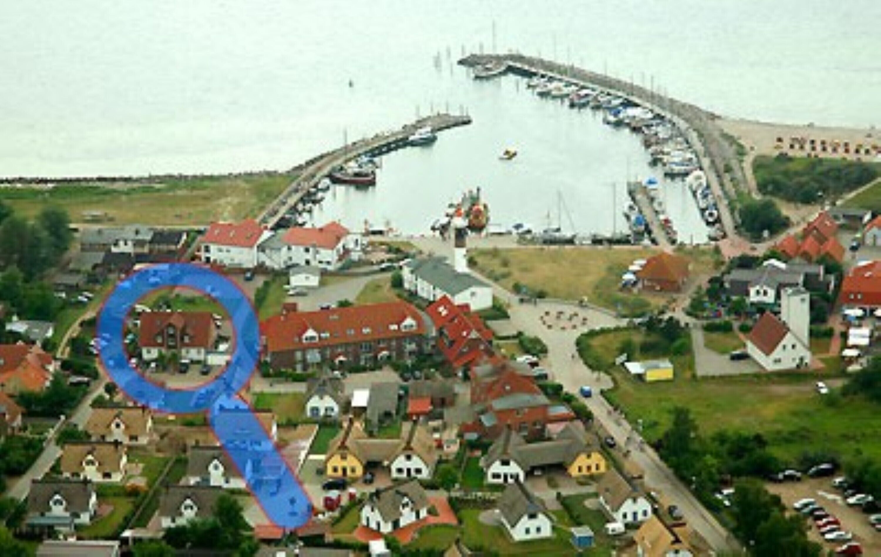 An aerial view of a coastal village with houses, a pier, and boats.