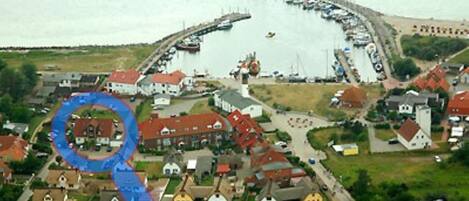 An aerial view of a coastal village with houses, a pier, and boats.