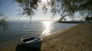 A boat tied to a sandy beach with a clear view of the water and distant mountains. - Villa Antonija, 50 m from sandy beach, heated pool, max 12 pax (Omis)
