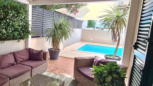 A covered patio with a pool, wicker furniture, and potted plants. - Villa Antonija, 50 m from sandy beach, heated pool, max 12 pax (Omis)