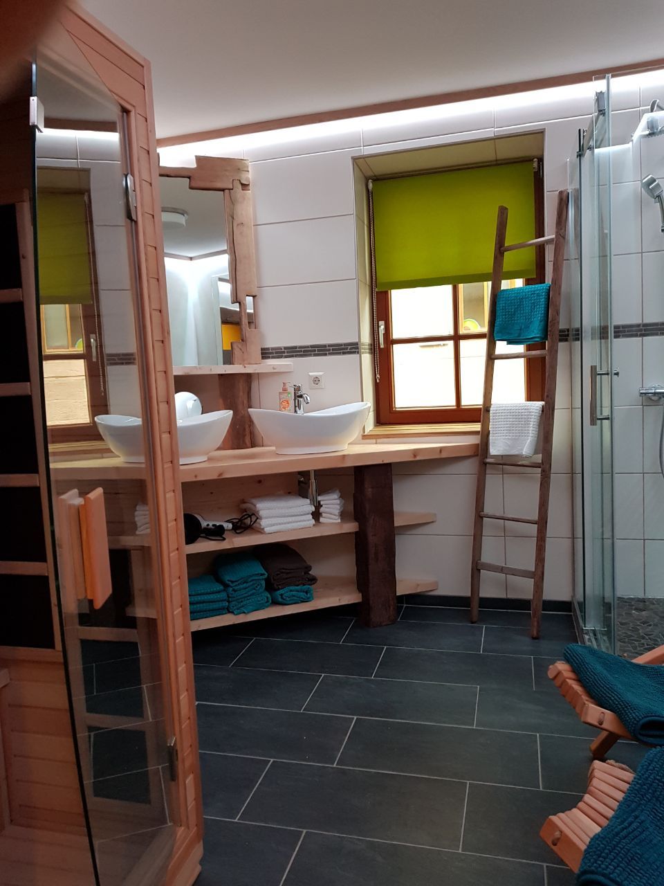 Une salle de bain compacte avec un meuble-lavabo en bois, deux vasques, une échelle et un espace douche.