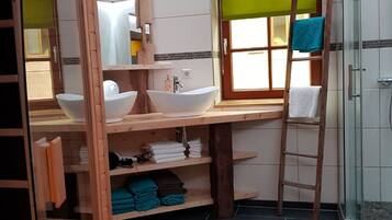 Une salle de bain compacte avec un meuble-lavabo en bois, deux vasques, une échelle et un espace douche.