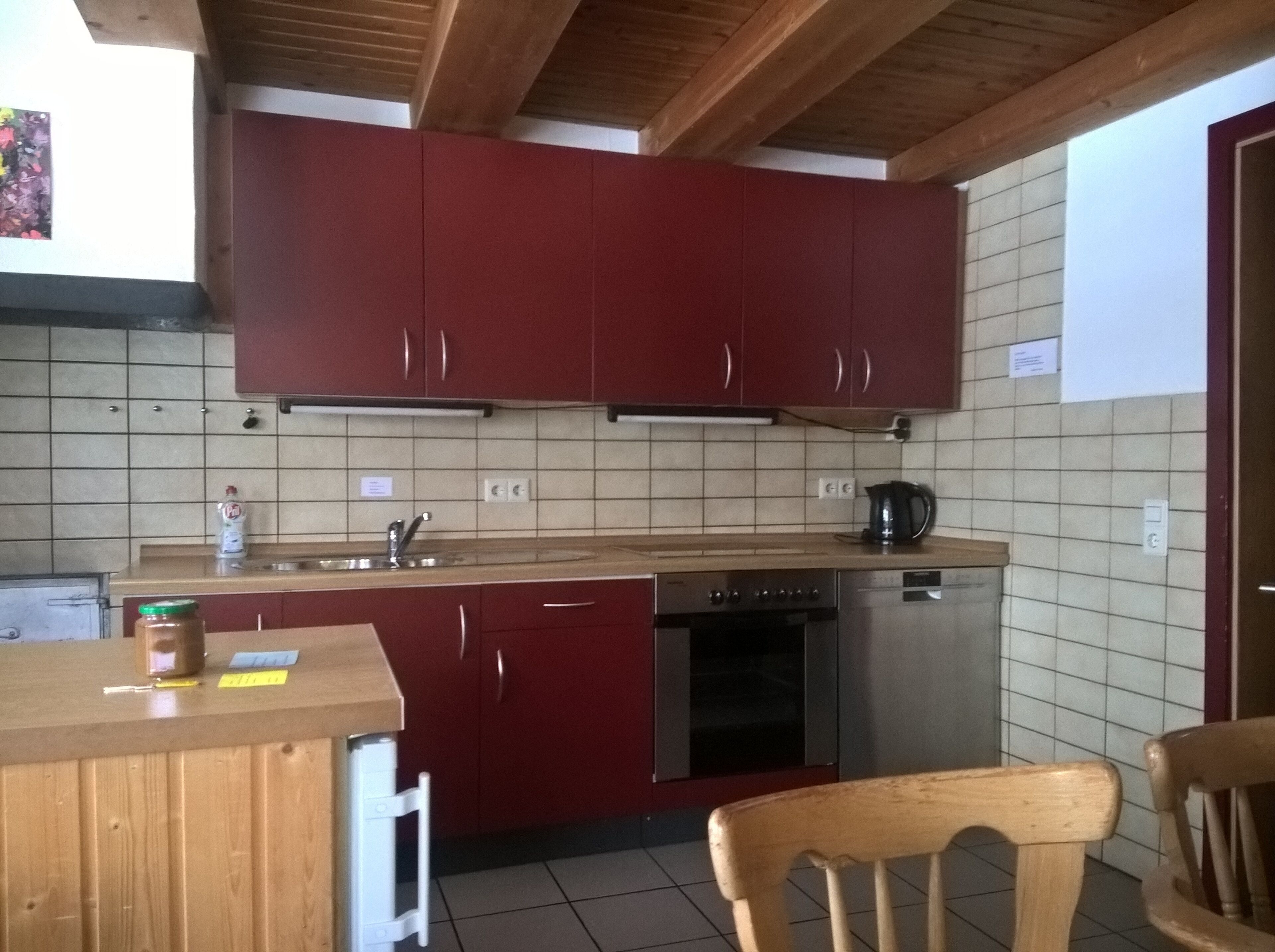 Eine Küche mit roten Schränken, einer Holz Arbeitsplatte, einer Spüle, einem Herd und einem Geschirrspüler.