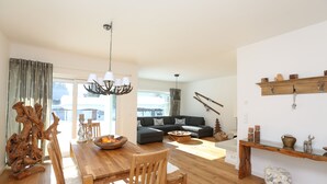 A spacious living room with a wooden dining table, a sofa, and a chandelier. - New holiday home in the mountains, Bad Mitterndorf, Sonnenalm (Bad Mitterndorf)