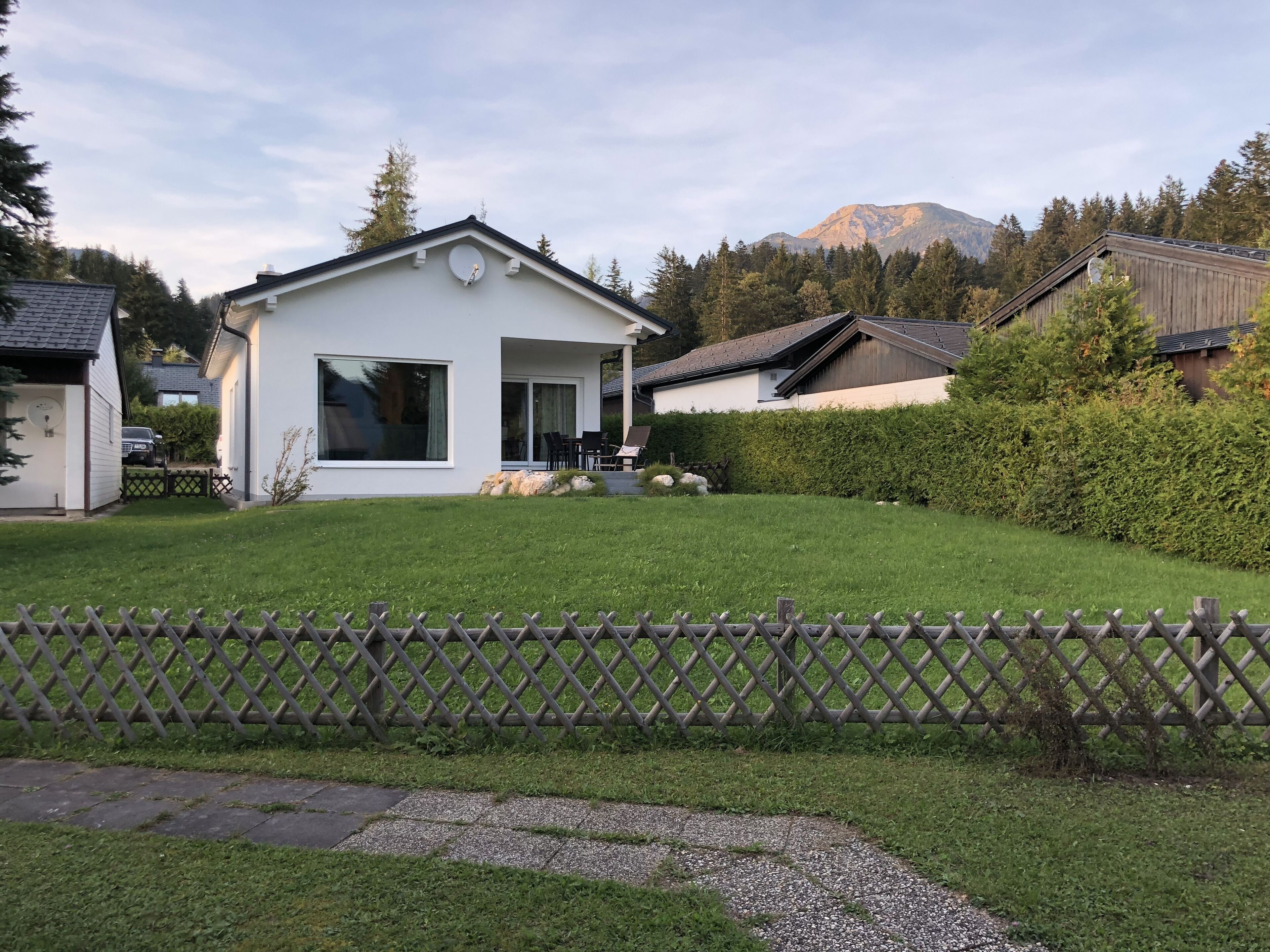 A modern house with a white exterior, a covered porch, and a well-maintained lawn.
