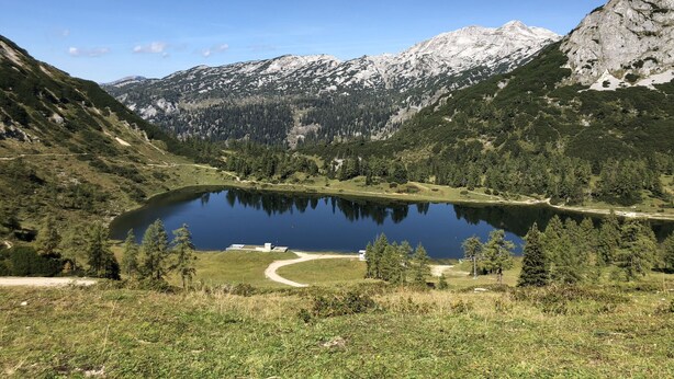 A mountain landscape with a lake, forested hills, and snow-capped peaks. - New holiday home in the mountains, Bad Mitterndorf, Sonnenalm (Bad Mitterndorf)