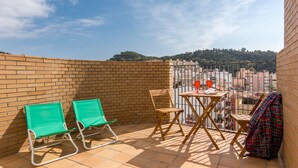 A balcony with two green chairs, a wooden chair, a small table, and a colorful blanket. - Central Apartment with Shared Terrace, Wi-Fi, Air Conditioning and TV (MALAGA)