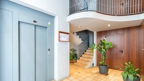 A modern interior with a staircase, potted plants, and a blue elevator. - Central Apartment with Shared Terrace, Wi-Fi, Air Conditioning and TV (MALAGA)