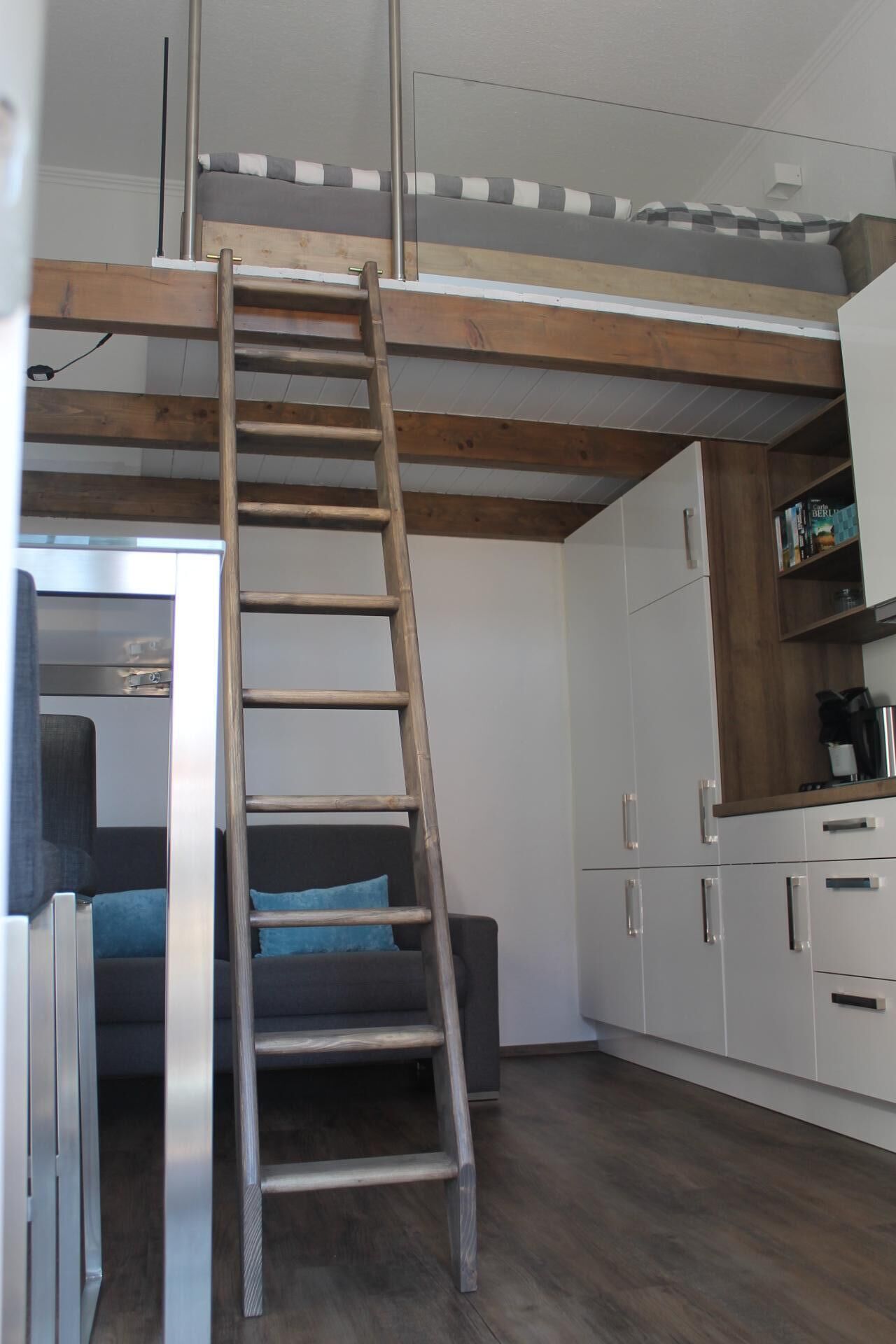 Un dormitori d'estil loft amb una escala de fusta que condueix a un espai de dormir en alt.
