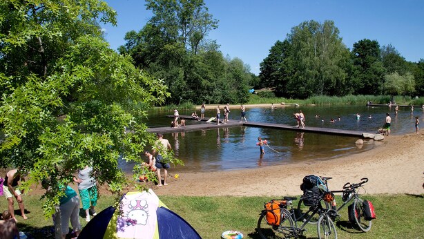 En campingplads med telte, en cykel og et badeområde.