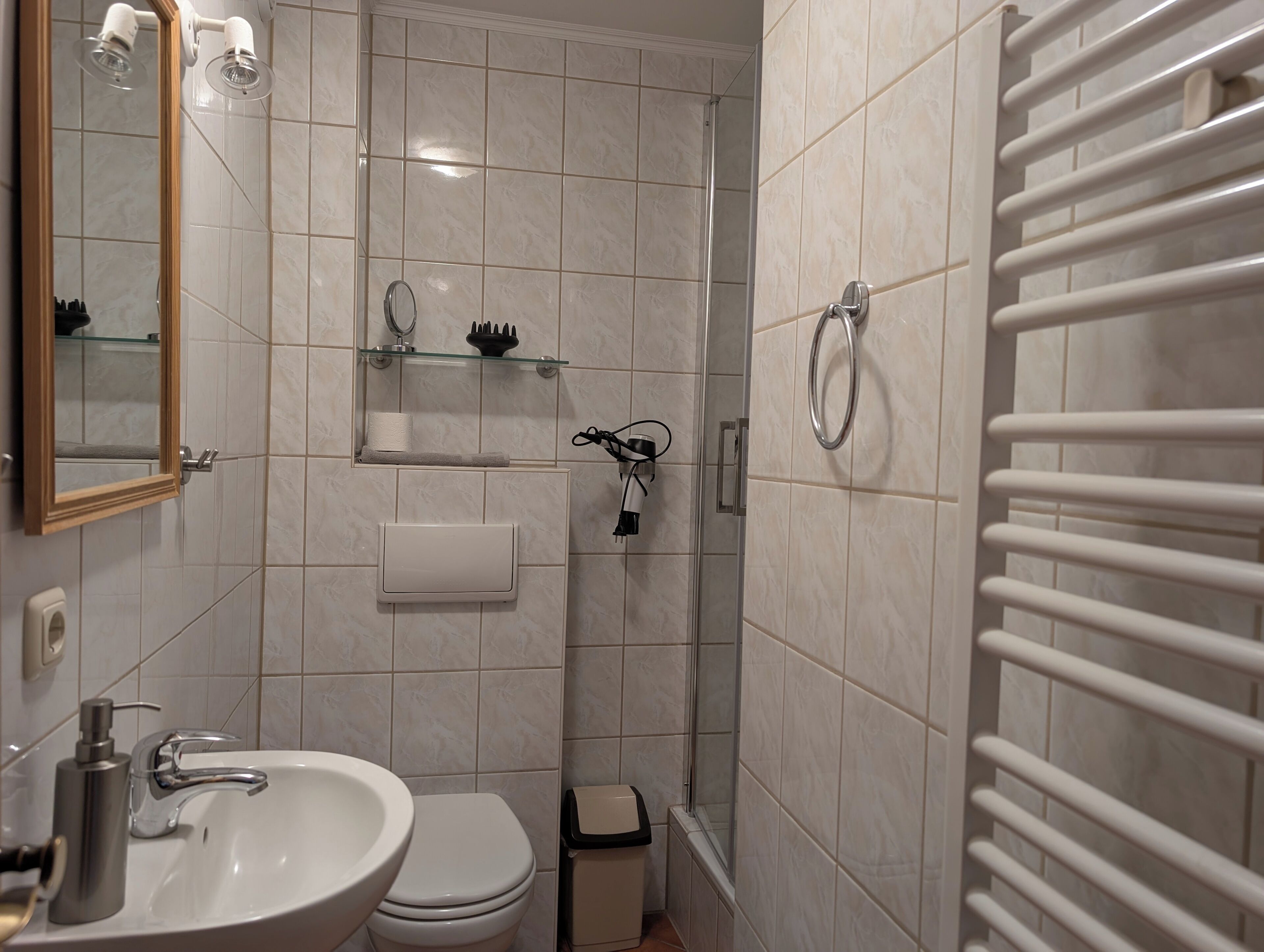 A bathroom with a sink, toilet, mirror, towel rack, and shower.