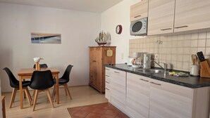 Une cuisine compacte avec un coin repas, comprenant un meuble en bois, un four à micro-ondes et une machine à café.