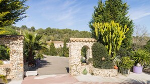 A stone archway leading to a garden with cacti and potted plants. - Finca Can Pep (Sant Joan)