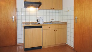 Une cuisine compacte avec des meubles en bois, un lave-vaisselle encastré et un pare-feu en carrelage.