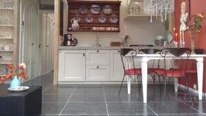 Uma cozinha com armários brancos, uma mesa de jantar com cadeiras e um lustre.