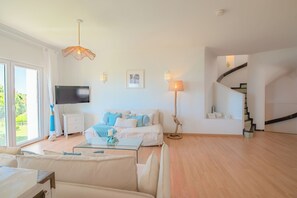 Una sala de estar moderna con un sofá, televisor y una escalera.
