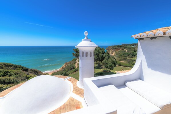 Un edificio blanco con vistas al mar y vegetación.