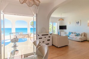 Una sala de estar con sofá, televisor y comedor con sillas y mesa.