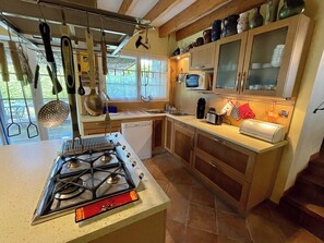 A kitchen with a gas stove, wooden cabinets, and a window overlooking a garden.
