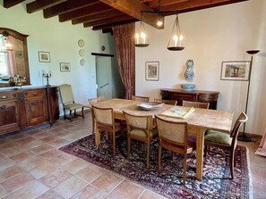 Un'area pranzo con un tavolo e sedie in legno, un tappeto decorato e un lampadario.