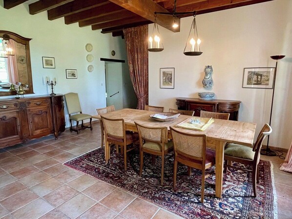 Un comedor con una mesa y sillas de madera, un tapete estampado y una lámpara de araña.