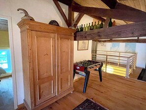 A wooden cabinet, a foosball table, and a balcony with bottles.