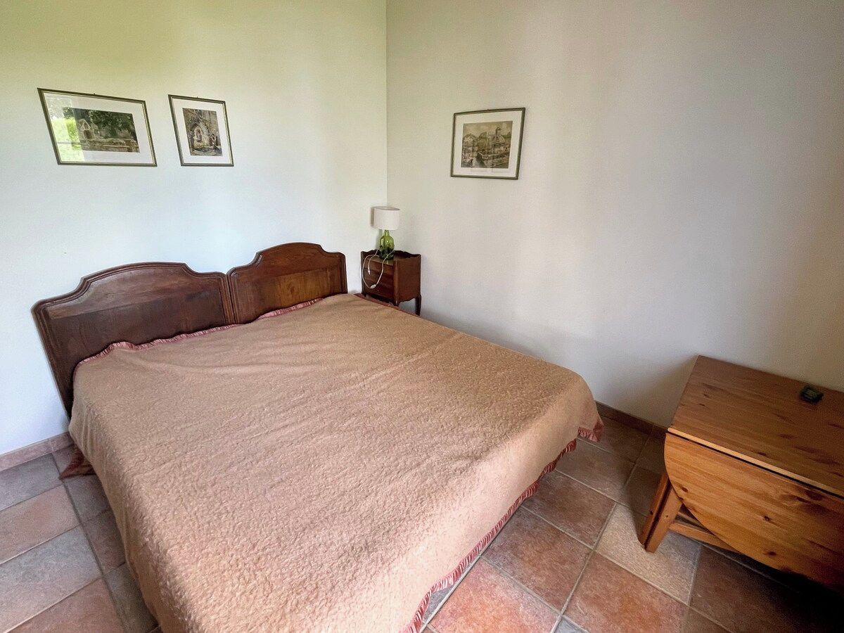 Une chambre à coucher avec un lit, une table de chevet, une lampe et une commode en bois.