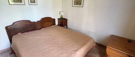 Une chambre à coucher avec un lit, une table de chevet, une lampe et une commode en bois.