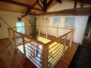 A wooden staircase with a metal railing leading to a loft area.