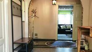A hallway with a patterned rug, a bench, a decorative light fixture, and an arched doorway leading to another room.