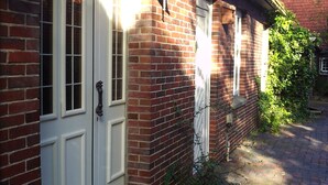 A brick building with a white door, a small porch, and a brick pathway.