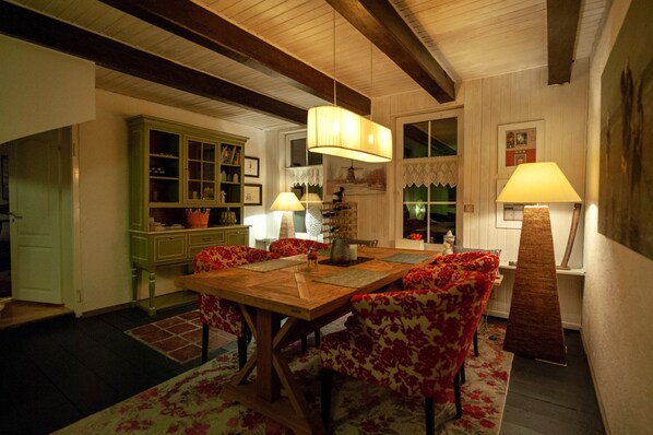 A dining area with a wooden table and floral-patterned chairs, a green cabinet, and two lamps.