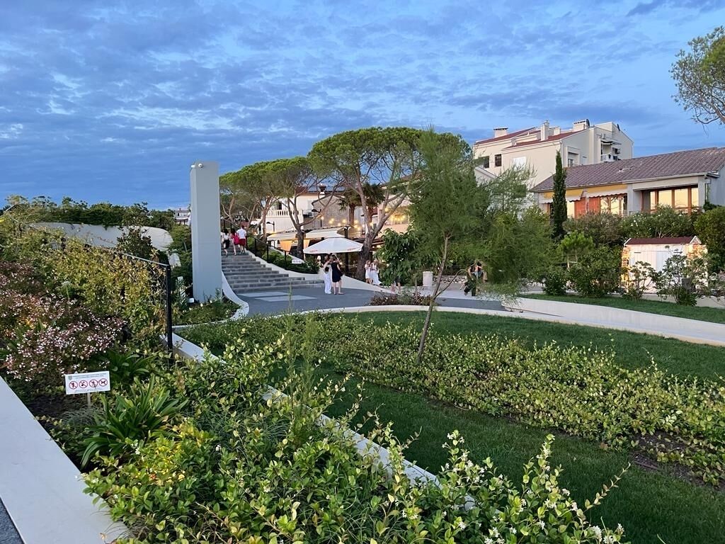 A landscaped area with a pathway leading to a building, surrounded by greenery and trees.