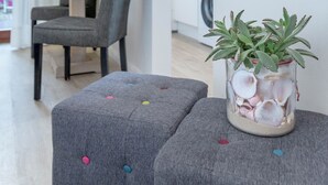 A modern living room with grey upholstered furniture, a decorative plant, and a wooden sign with directional arrows. - "Sea lights" apartment on Sylt for 2 people with garden in the city center (Sylt OT Westerland)