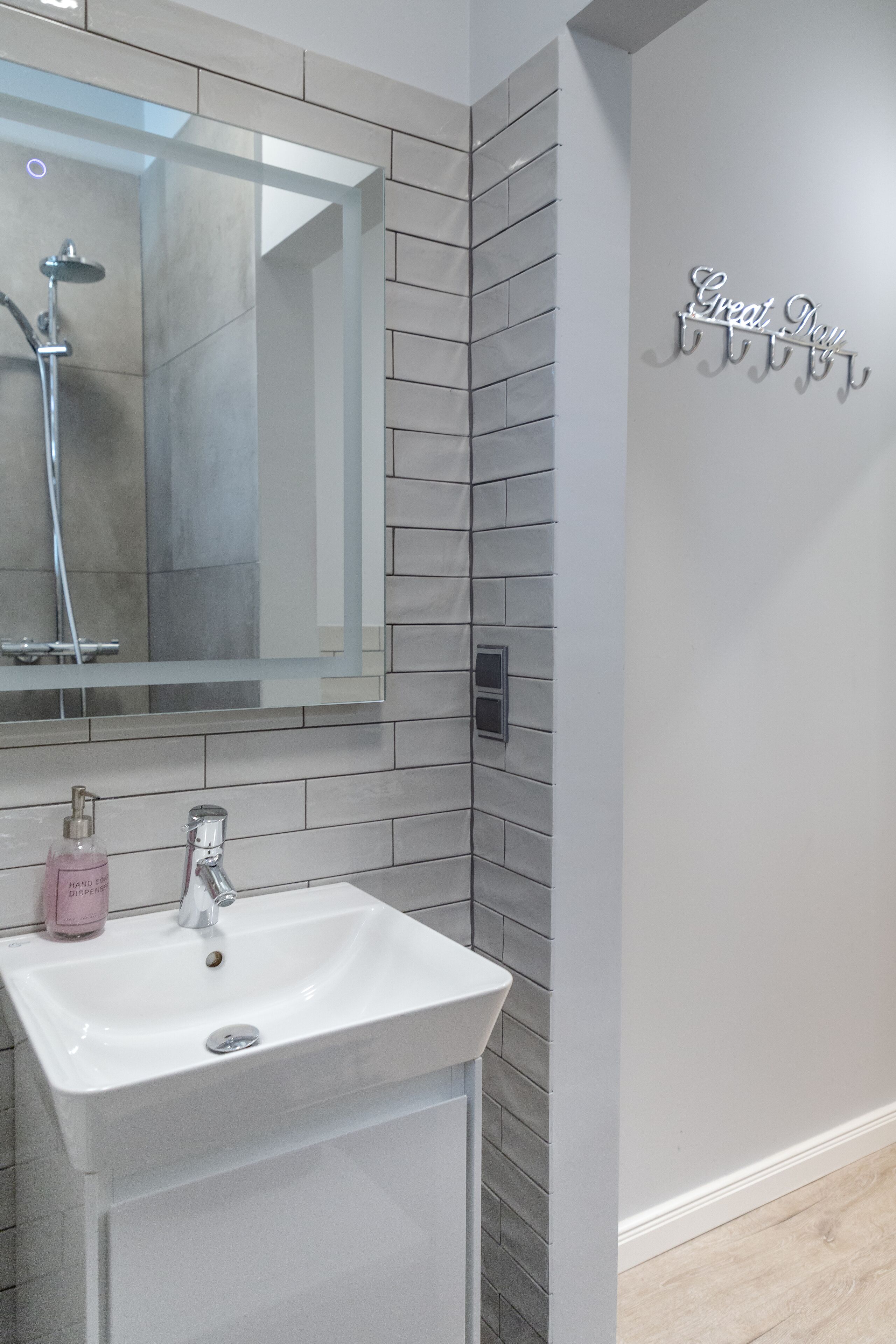 Une salle de bain avec un lavabo blanc, un miroir et une douche.