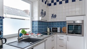 A modern kitchen with a stainless steel sink, white cabinets, and a Bosch oven. - "Sea lights" apartment on Sylt for 2 people with garden in the city center (Sylt OT Westerland)