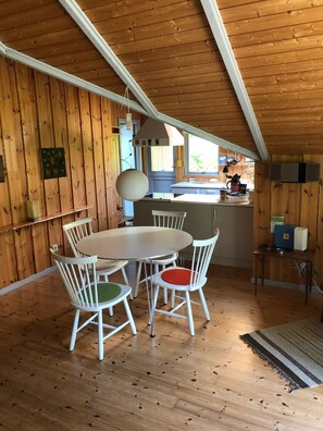Un interior de madera con comedor, cocina y techo inclinado.