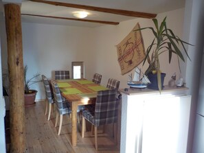 Un coin repas avec une table en bois, des chaises à carreaux et une plante en pot.