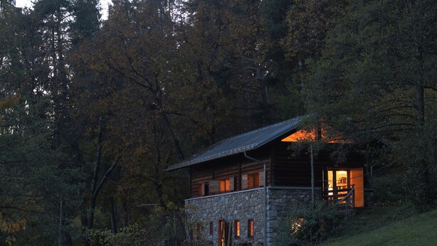A rustic cabin with a stone foundation and wooden exterior, surrounded by dense forest. -  Renovated in 2006, charming holiday home by the woods (Samone)