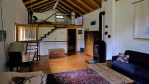 A spacious living area with wooden floors, a staircase leading to an upper level, a fireplace, and a sofa. -  Renovated in 2006, charming holiday home by the woods (Samone)