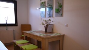 A dining area with a wooden table, two benches with green cushions, and a vase with branches.